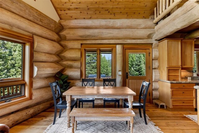 dining area with lofted ceiling, rustic walls, and light hardwood / wood-style flooring