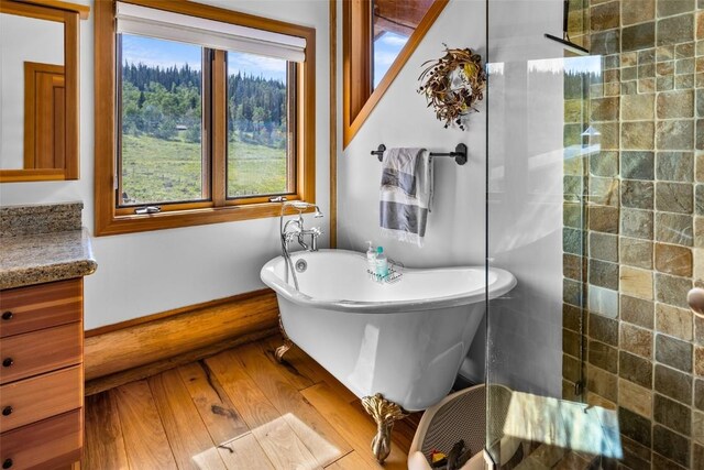 bathroom with hardwood / wood-style flooring, vanity, and shower with separate bathtub