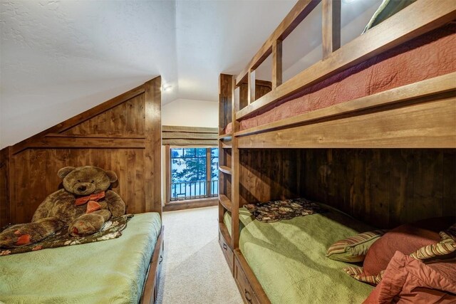 bedroom featuring wood walls, lofted ceiling, and light carpet