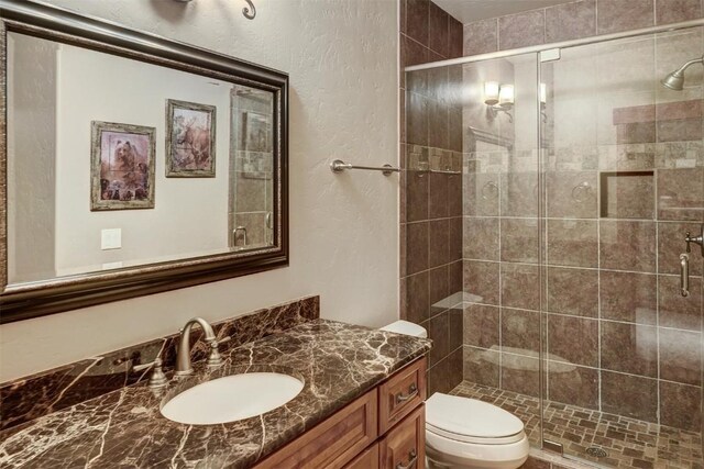 bathroom featuring walk in shower, vanity, and toilet