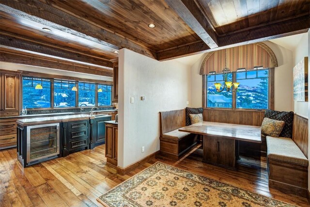 sitting room with breakfast area, wood ceiling, beverage cooler, hardwood / wood-style flooring, and beamed ceiling