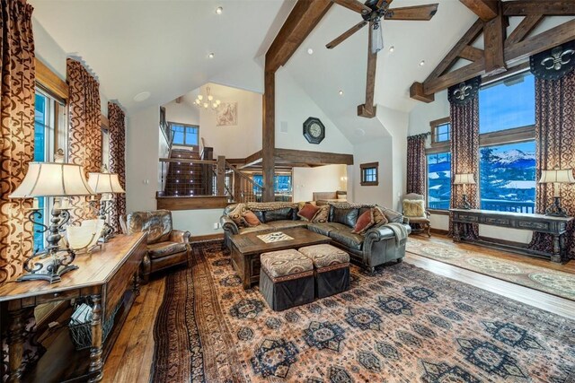 living room with a healthy amount of sunlight, beamed ceiling, high vaulted ceiling, ceiling fan with notable chandelier, and hardwood / wood-style flooring