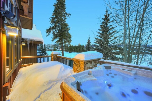 snow covered deck with a hot tub