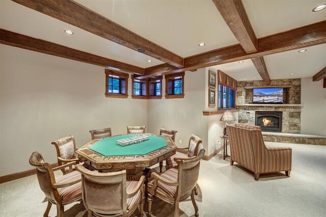 rec room with beamed ceiling, a stone fireplace, and light colored carpet