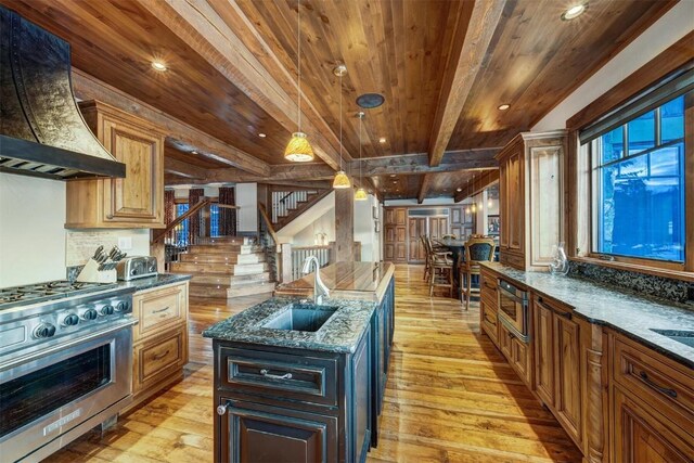 kitchen with beam ceiling, sink, backsplash, range with two ovens, and custom exhaust hood