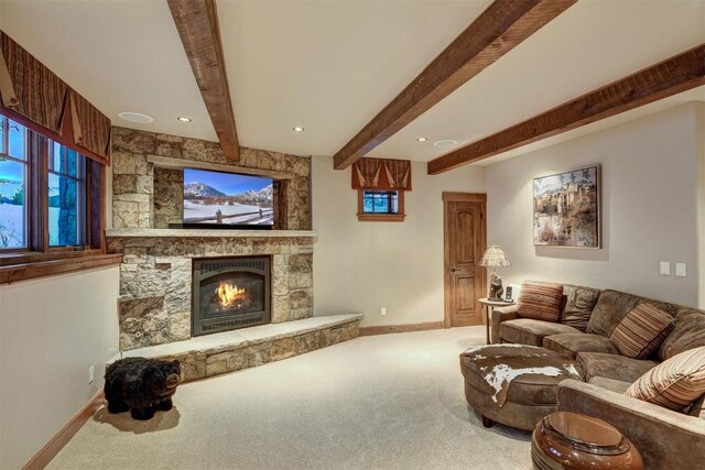 carpeted living room featuring beam ceiling and a stone fireplace