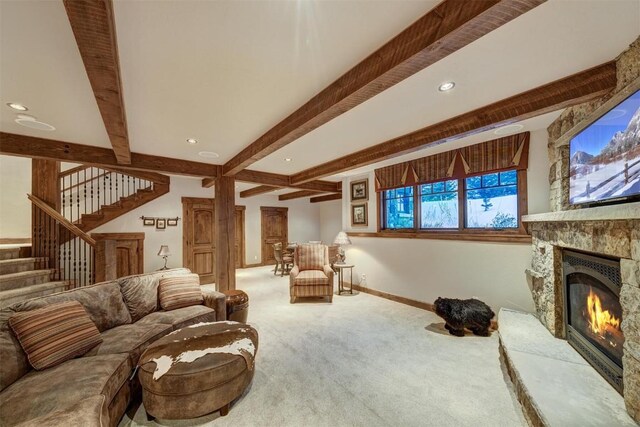 living room featuring beam ceiling, a stone fireplace, and carpet