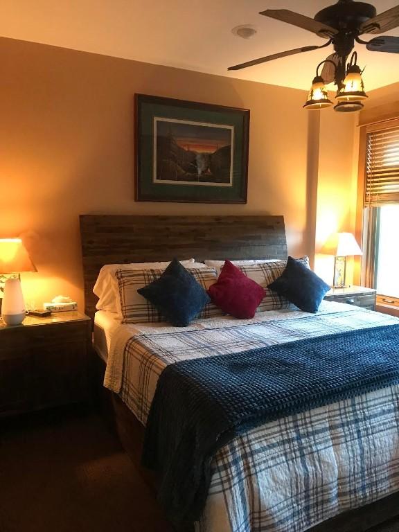 bedroom featuring ceiling fan with notable chandelier