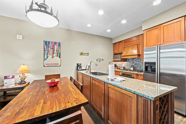 kitchen featuring custom exhaust hood, sink, decorative backsplash, appliances with stainless steel finishes, and light stone counters