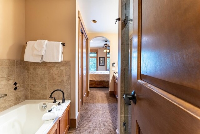 bathroom featuring ceiling fan, a tub, and vanity