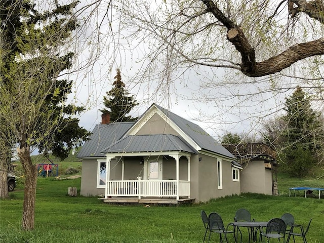 view of front of property featuring stucco siding, a trampoline, a porch, and a front yard