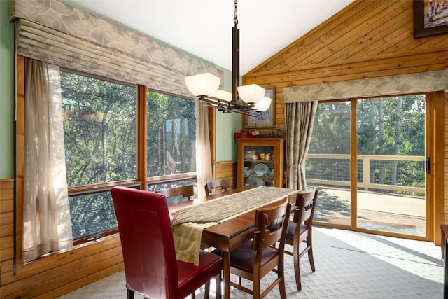 dining room with wooden walls, vaulted ceiling, and a notable chandelier