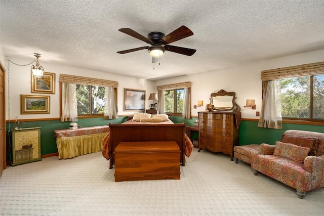 bedroom featuring ceiling fan, light carpet, and a textured ceiling