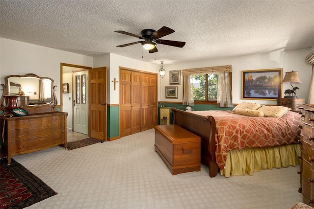 carpeted bedroom with a textured ceiling, ceiling fan, and a closet