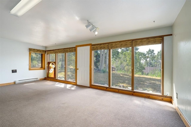 carpeted spare room featuring track lighting and a baseboard heating unit