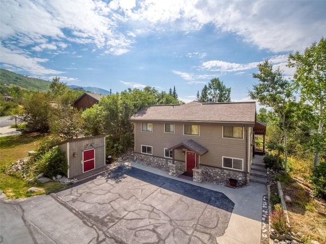 view of front of home featuring a mountain view and a storage shed