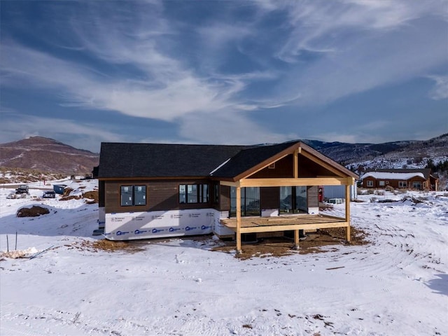 snow covered rear of property featuring a mountain view