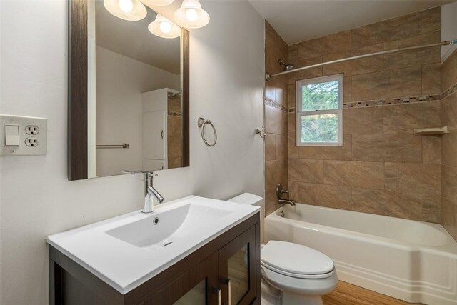 full bathroom with vanity, tiled shower / bath combo, and toilet