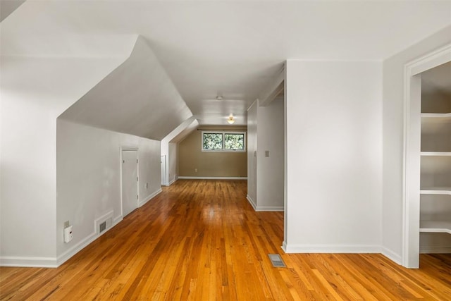 additional living space featuring light wood-type flooring and vaulted ceiling