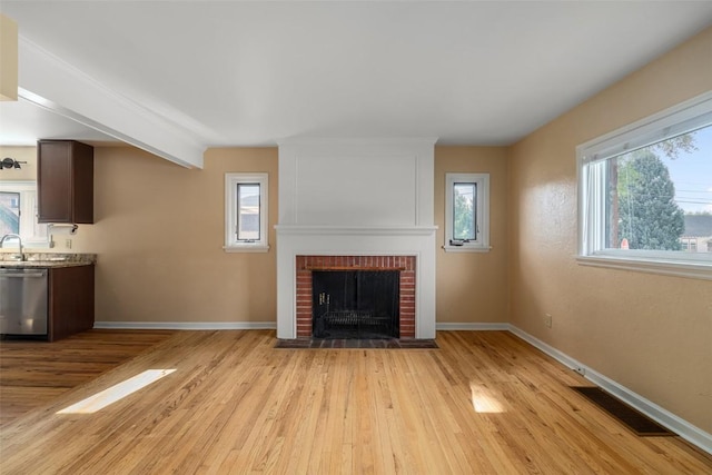 unfurnished living room with light hardwood / wood-style floors, sink, and a fireplace