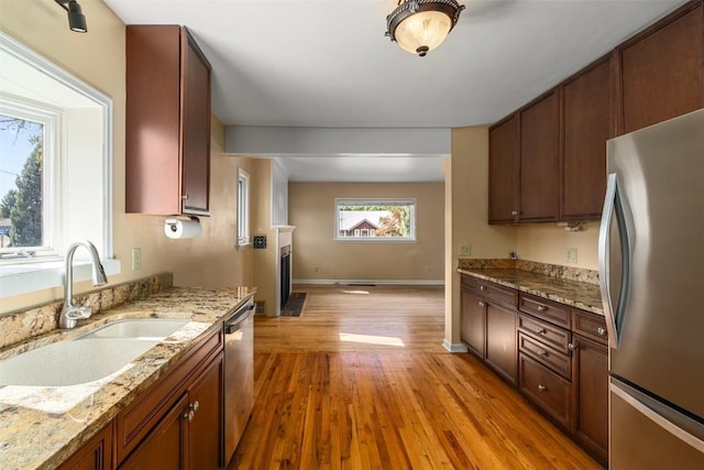 kitchen featuring light stone counters, light wood-type flooring, sink, and appliances with stainless steel finishes