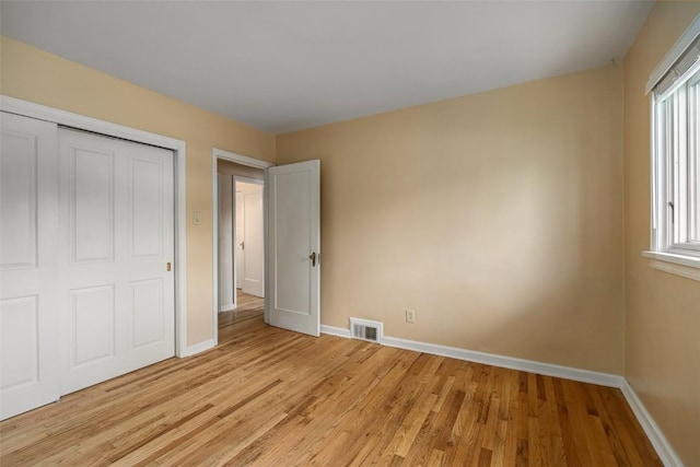 unfurnished bedroom featuring multiple windows, light hardwood / wood-style flooring, and a closet