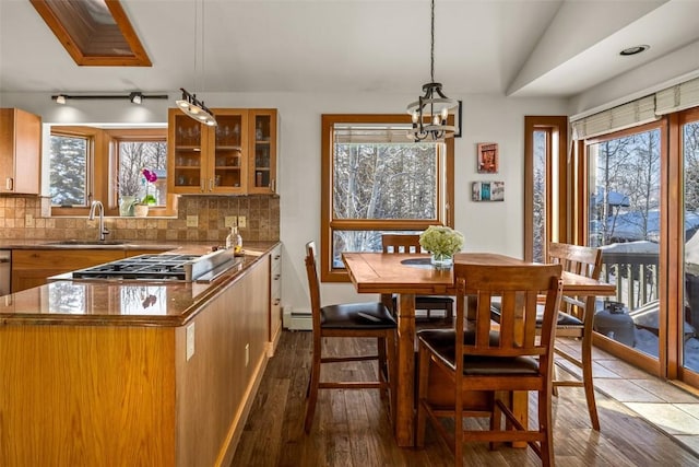 kitchen with hanging light fixtures, sink, hardwood / wood-style floors, and decorative backsplash