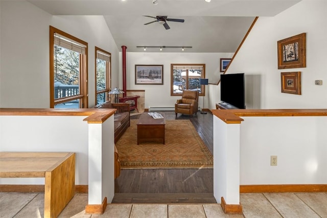 tiled living room featuring a baseboard radiator, lofted ceiling, plenty of natural light, and ceiling fan