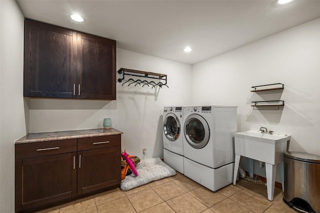 laundry area with cabinets, light tile patterned floors, and washer and clothes dryer