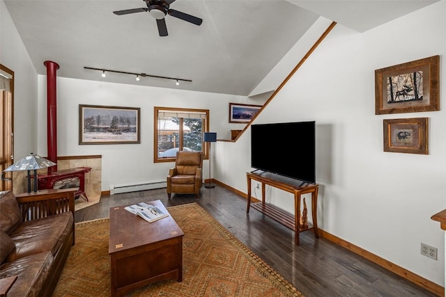 living room with dark wood-type flooring, a wood stove, baseboard heating, track lighting, and ceiling fan