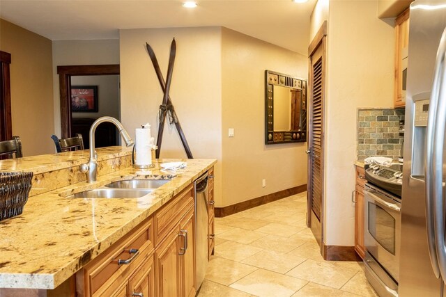 kitchen with a breakfast bar, a center island with sink, sink, tasteful backsplash, and stainless steel appliances