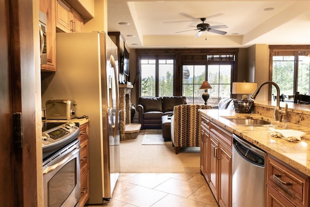 kitchen with stove, stainless steel dishwasher, a tray ceiling, ceiling fan, and sink