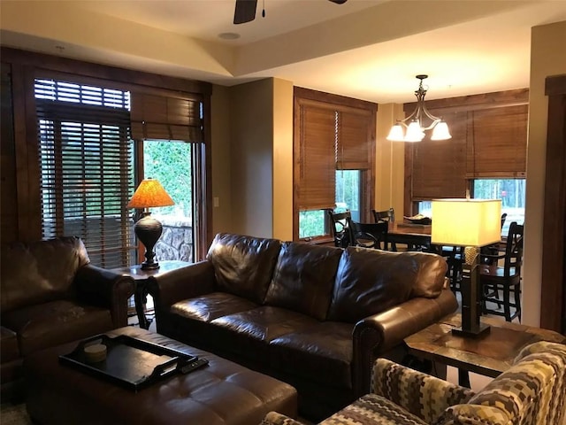 living room with ceiling fan with notable chandelier and wooden walls