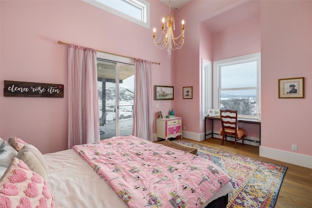 bedroom featuring a baseboard radiator, wood finished floors, baseboards, access to outside, and an inviting chandelier