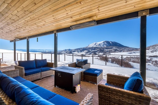 snow covered patio featuring an outdoor living space with a fire pit and a mountain view