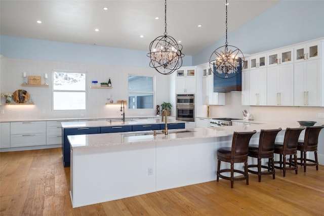 kitchen with white cabinetry, stainless steel double oven, decorative backsplash, decorative light fixtures, and sink