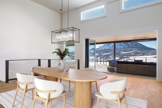 dining room featuring light wood-style flooring, a high ceiling, and a mountain view