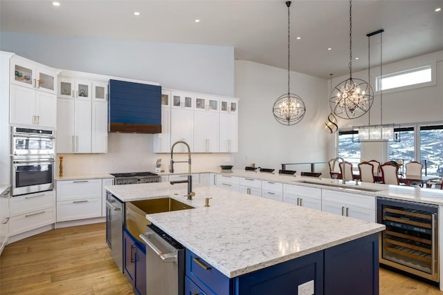 kitchen featuring decorative light fixtures, wine cooler, sink, a center island with sink, and blue cabinets