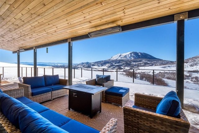 snow covered patio featuring an outdoor living space with a fire pit and a mountain view