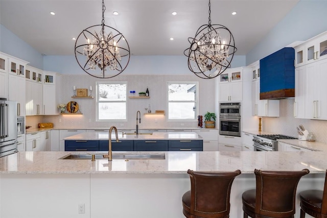 kitchen featuring pendant lighting, white cabinets, premium appliances, sink, and blue cabinets