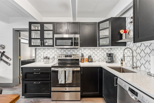 kitchen with tasteful backsplash, sink, beam ceiling, and appliances with stainless steel finishes