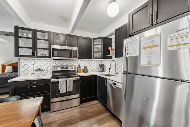 kitchen featuring sink, dark wood-type flooring, appliances with stainless steel finishes, tasteful backsplash, and beamed ceiling