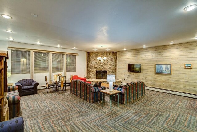 living room with wooden walls, dark colored carpet, a baseboard radiator, a notable chandelier, and a wood stove