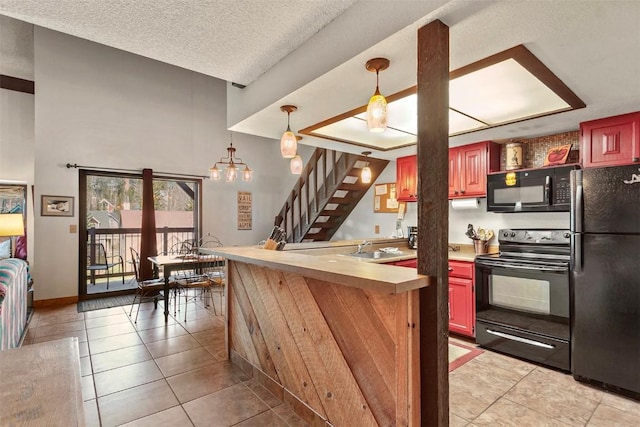 kitchen with black appliances, sink, hanging light fixtures, light tile patterned floors, and a textured ceiling