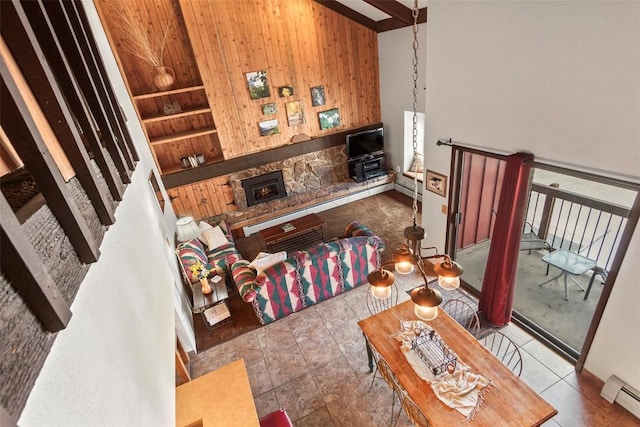 tiled living room with baseboard heating, a stone fireplace, built in features, beamed ceiling, and wood walls