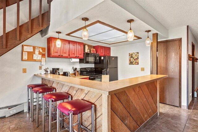 kitchen with kitchen peninsula, a kitchen bar, a textured ceiling, black appliances, and decorative light fixtures