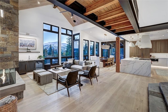 living room with wood ceiling, beam ceiling, high vaulted ceiling, light hardwood / wood-style flooring, and a mountain view