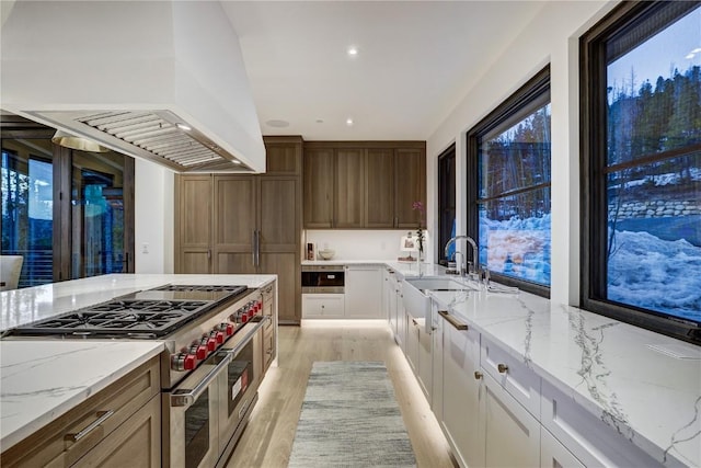 kitchen featuring white cabinetry, island range hood, light stone countertops, and range with two ovens