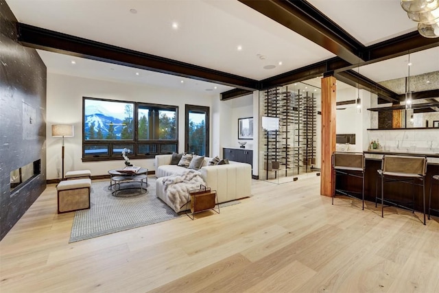 living room with beam ceiling, a fireplace, and light hardwood / wood-style floors