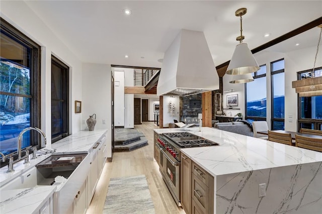 kitchen with premium range hood, light stone counters, pendant lighting, double oven range, and white cabinets